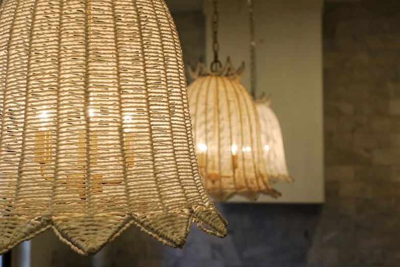 a hanging light and wicker lamps on a stone wall