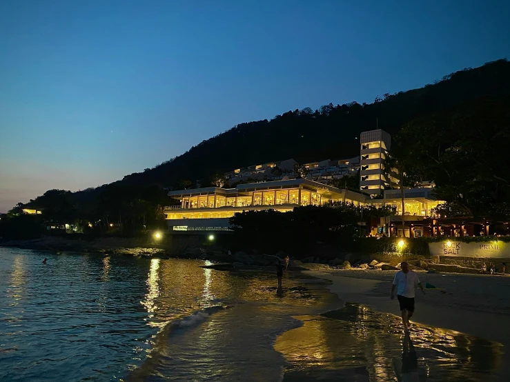 a group of people walking along a beach in the evening