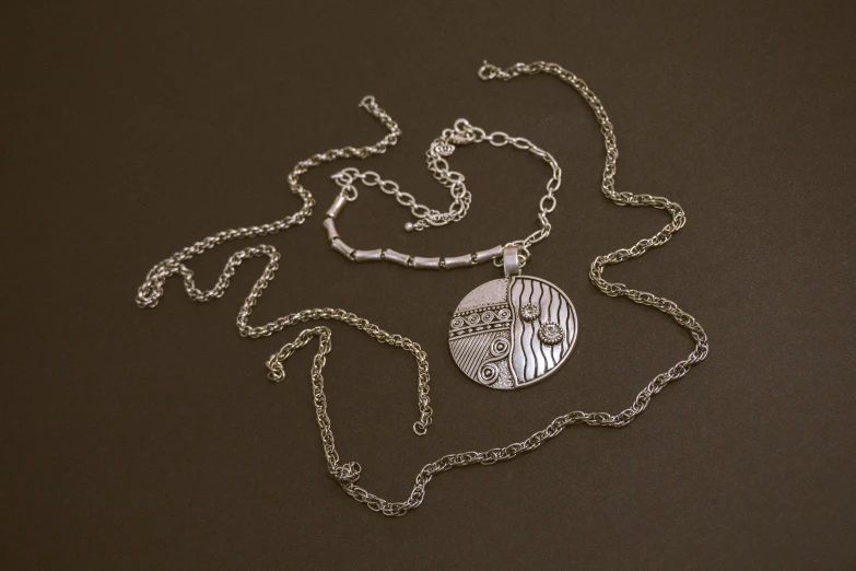 a small silver medallion is on a chain