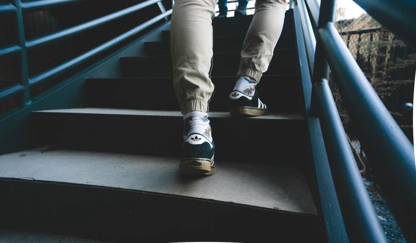 person in white shirt and brown pants walking down stairs