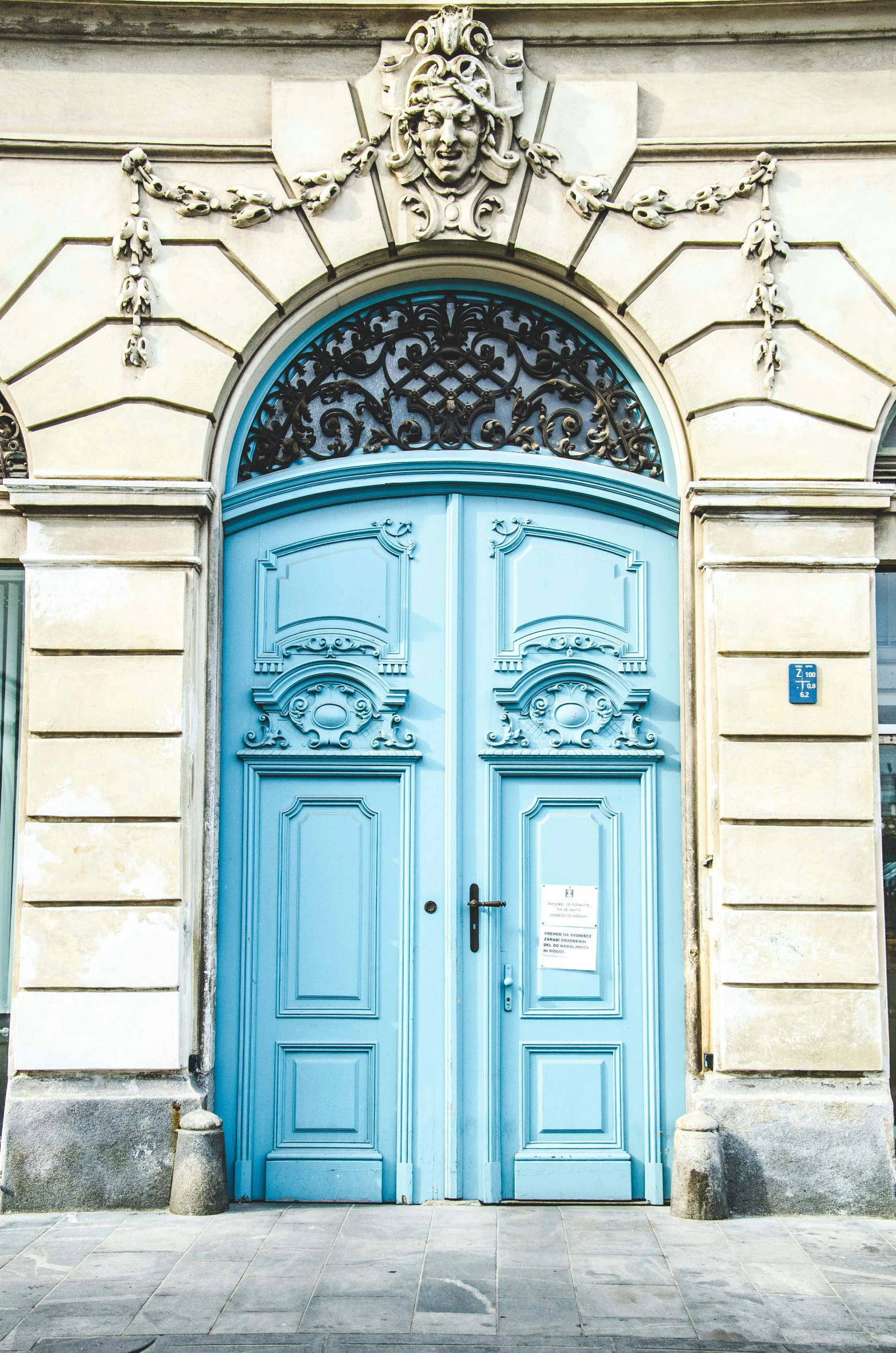 blue double doors on a beige building with iron decorations