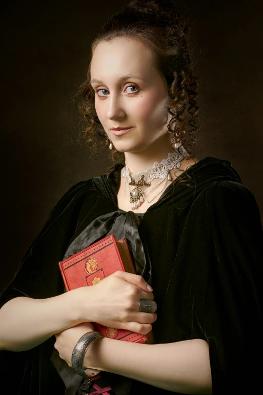 a woman in a black dress holding an orange book