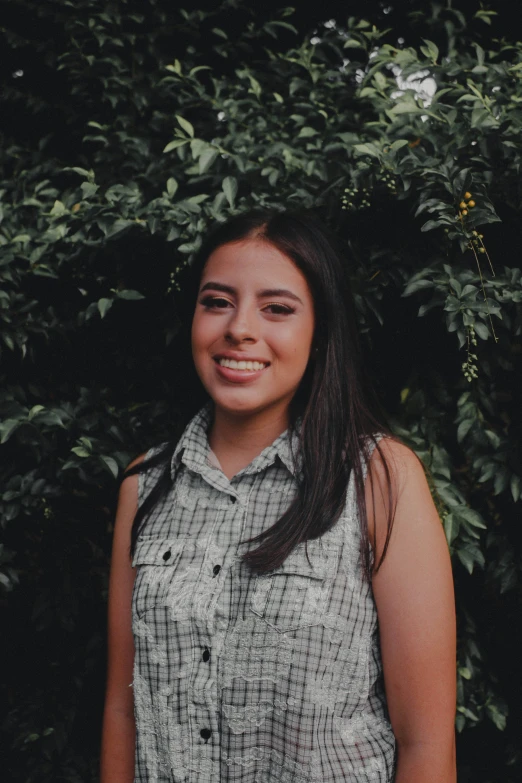 a woman with long hair is smiling in front of a tree