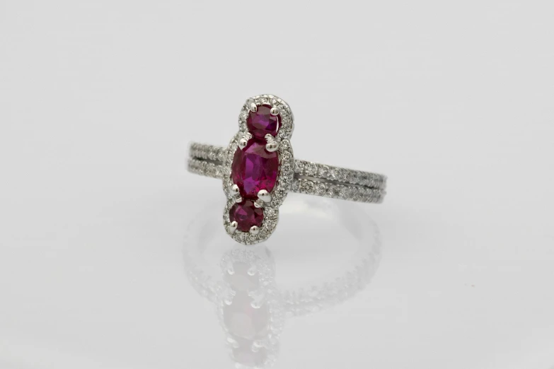 a white gold ring with an oval pink sapphire in it