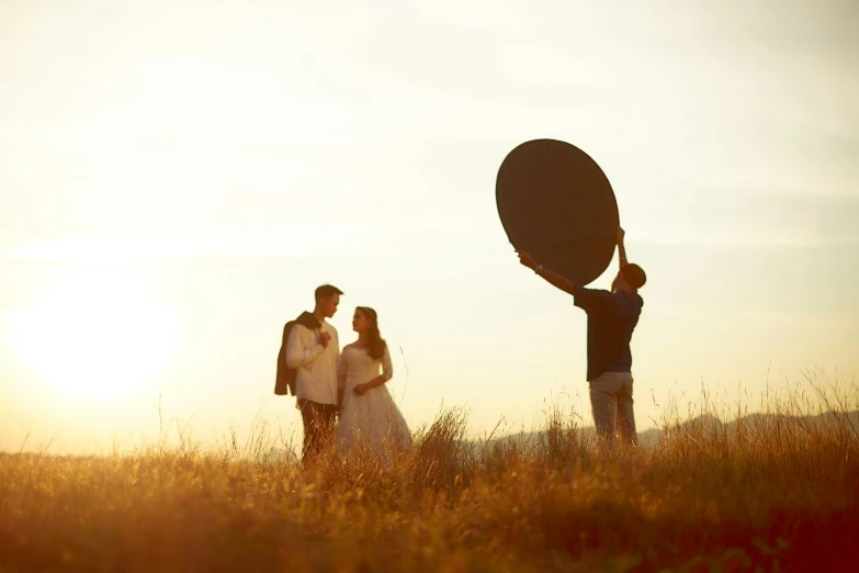 a couple stand in a field holding a frisbee