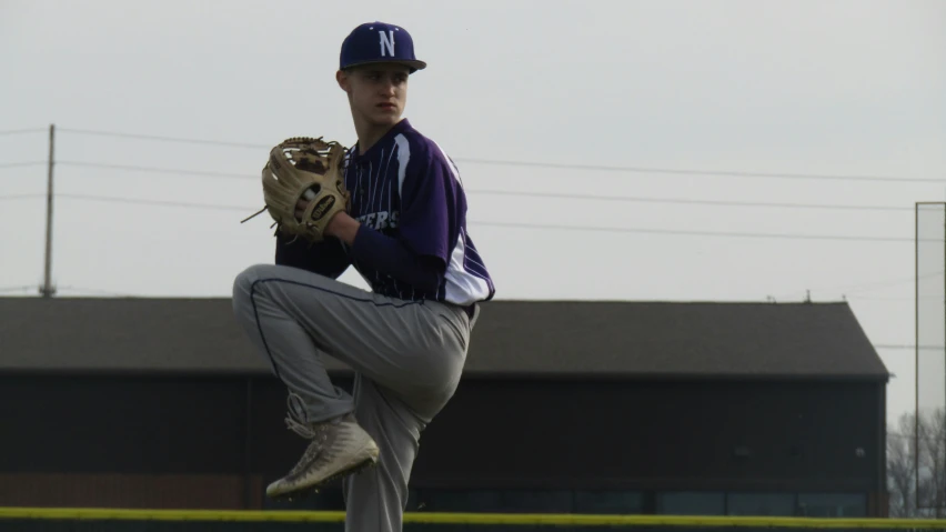 a young man in a baseball uniform is throwing a pitch