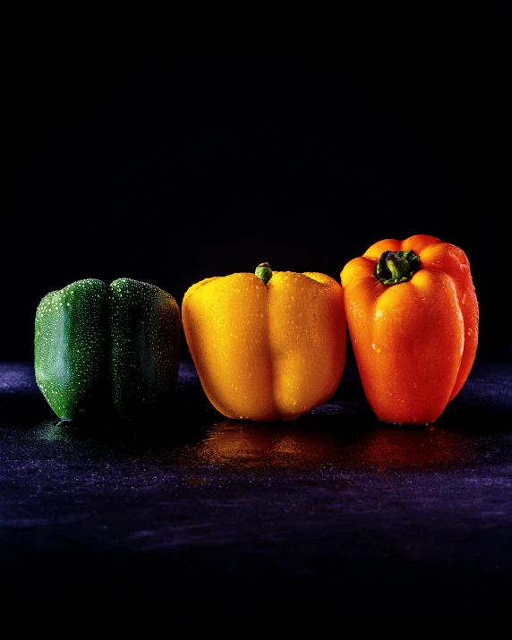 three peppers with different colors sit next to each other