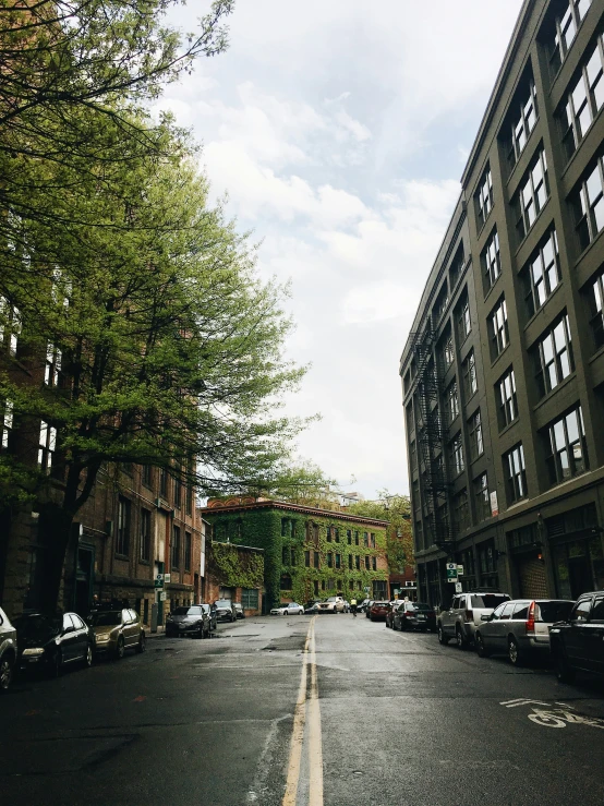 an empty city street with several vehicles parked on it