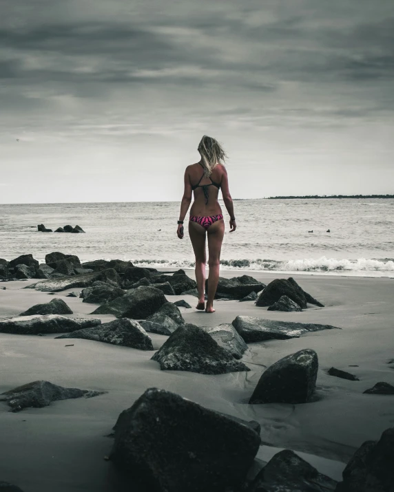 a beautiful woman in a bathing suit walking across rocks