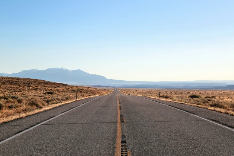 the empty road has mountains on both sides