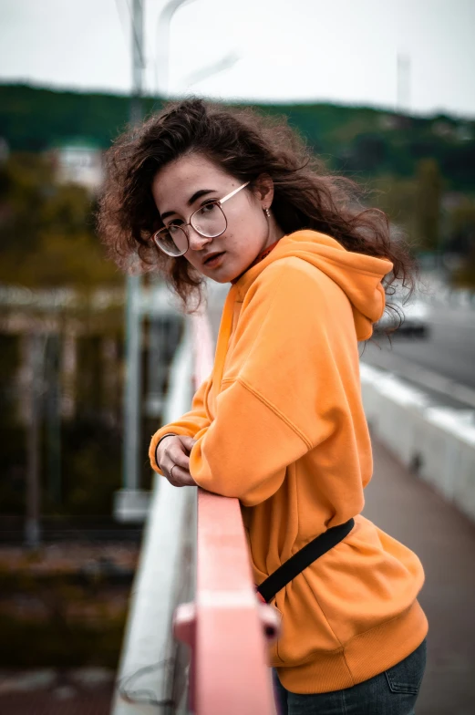 a girl is standing on the side of a bridge