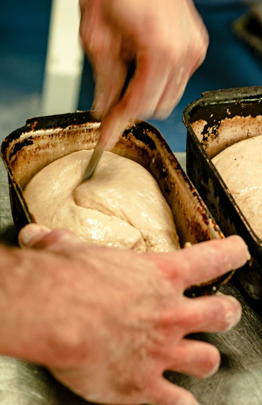 a person using a large knife to cut bread