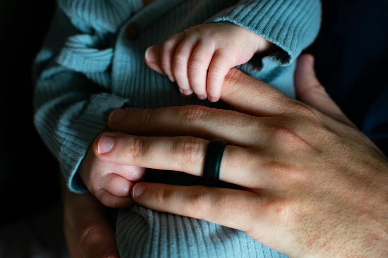 a baby wearing an adjustable ring being held in someones hand