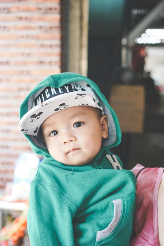 the little boy is wearing a cap and a green sweatshirt