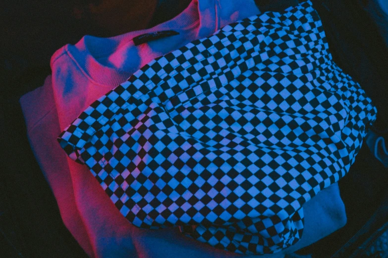 a checkered bag on a blanket with a pink light shining behind it