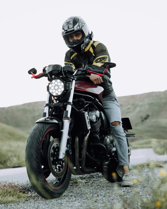 a man wearing a helmet and leather jacket sits on a black motorcycle