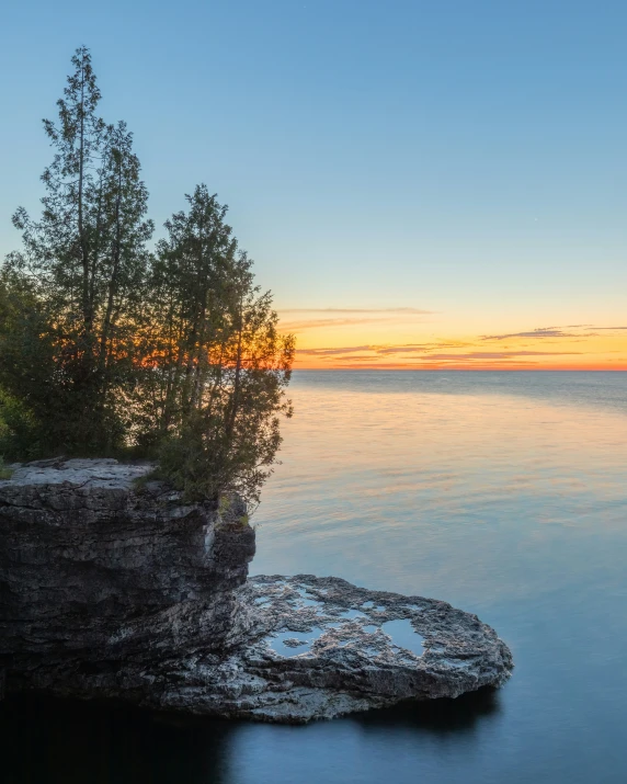 some kind of rocks on a shore with water at sunset