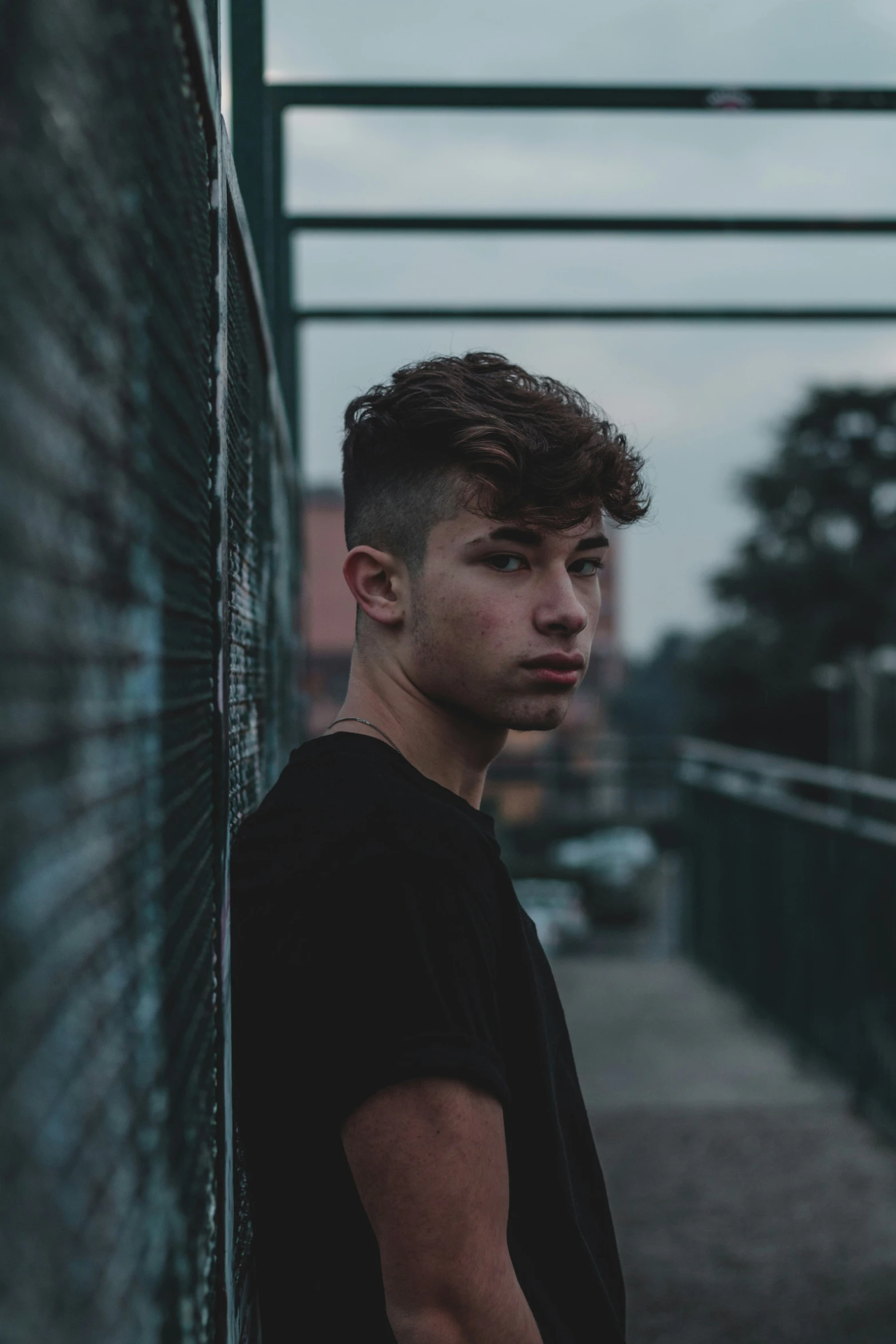 a young man leans against the wall of an alleyway