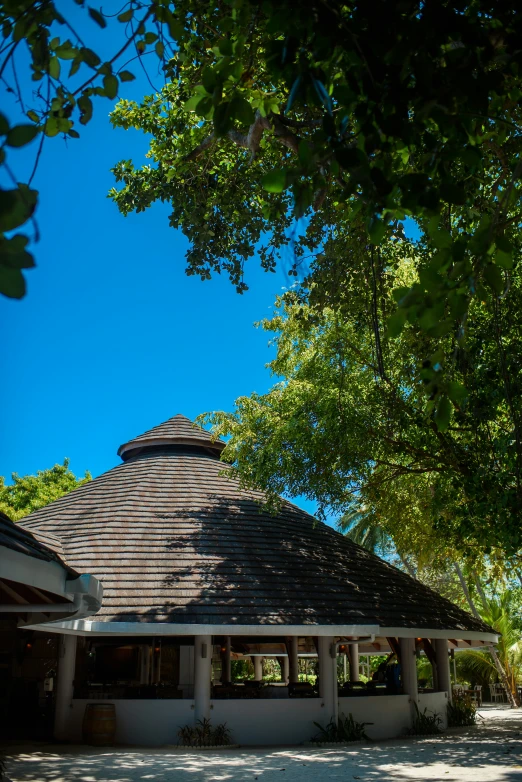 the roof of a small round white building with green trees and blue sky