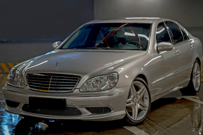 an silver mercedes with the headlights on at night