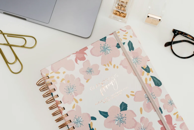 a flower notebook with floral cover and clear glasses