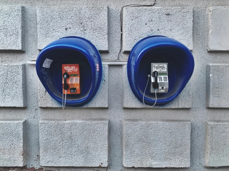 two gray and blue double parking meters on a brick wall