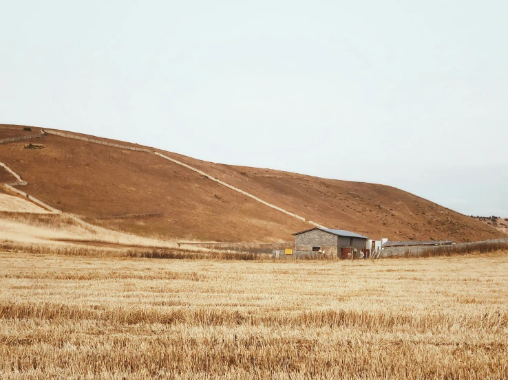 a small house on the hill with a very brown roof