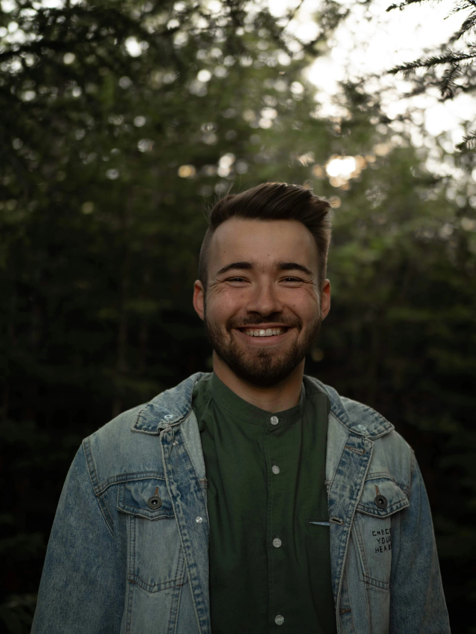 a man smiling in front of a grove of trees