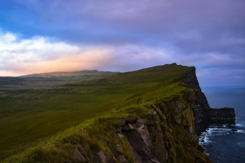 a large grassy cliff next to an ocean