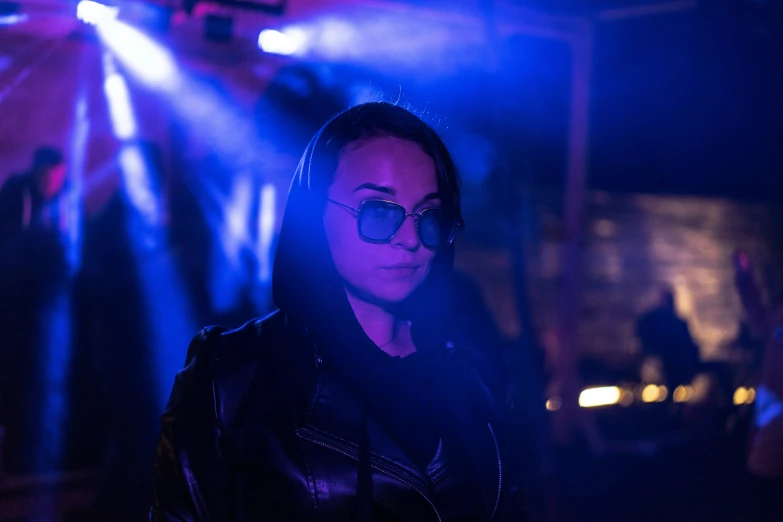 a person wearing sunglasses on a stage and blue lights behind them