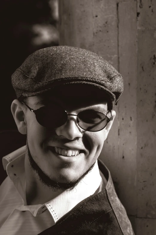 a smiling young man wearing glasses and a hat