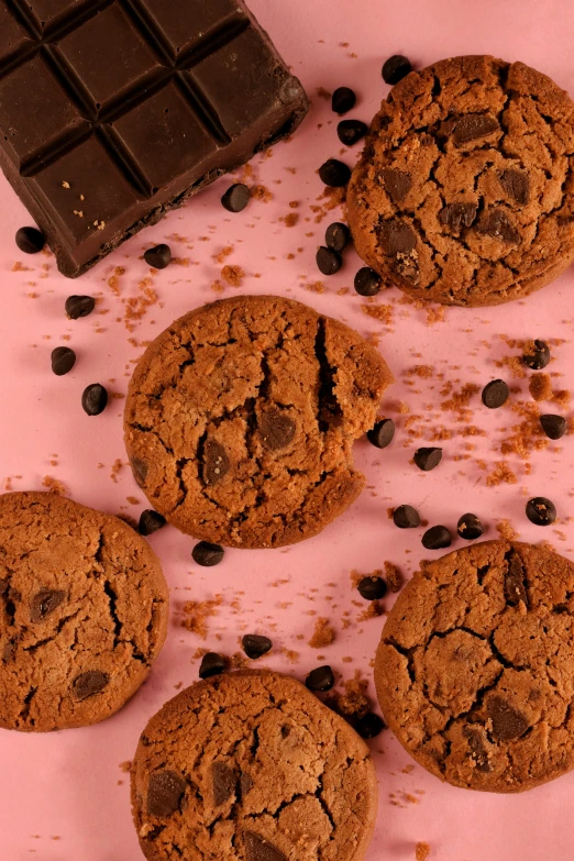 four chocolate cookies sitting on a pink surface