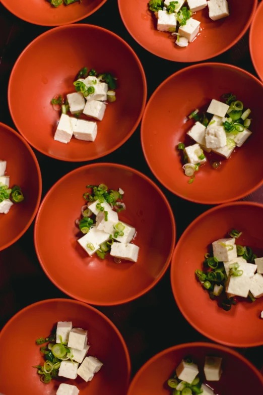 many orange bowls are holding some food on red plates