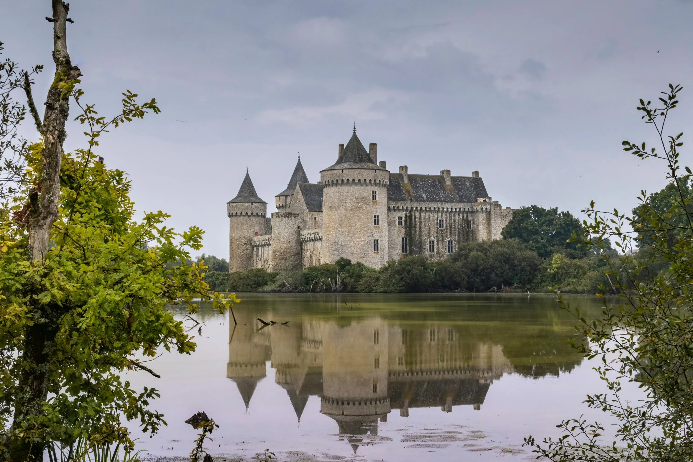 the castle looks out over a lake on a cloudy day