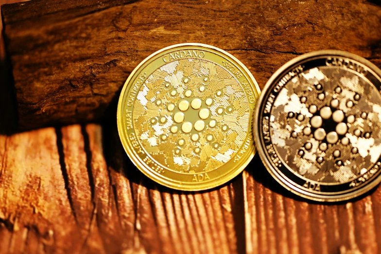 two gold and silver colored coin sitting on top of a wooden table