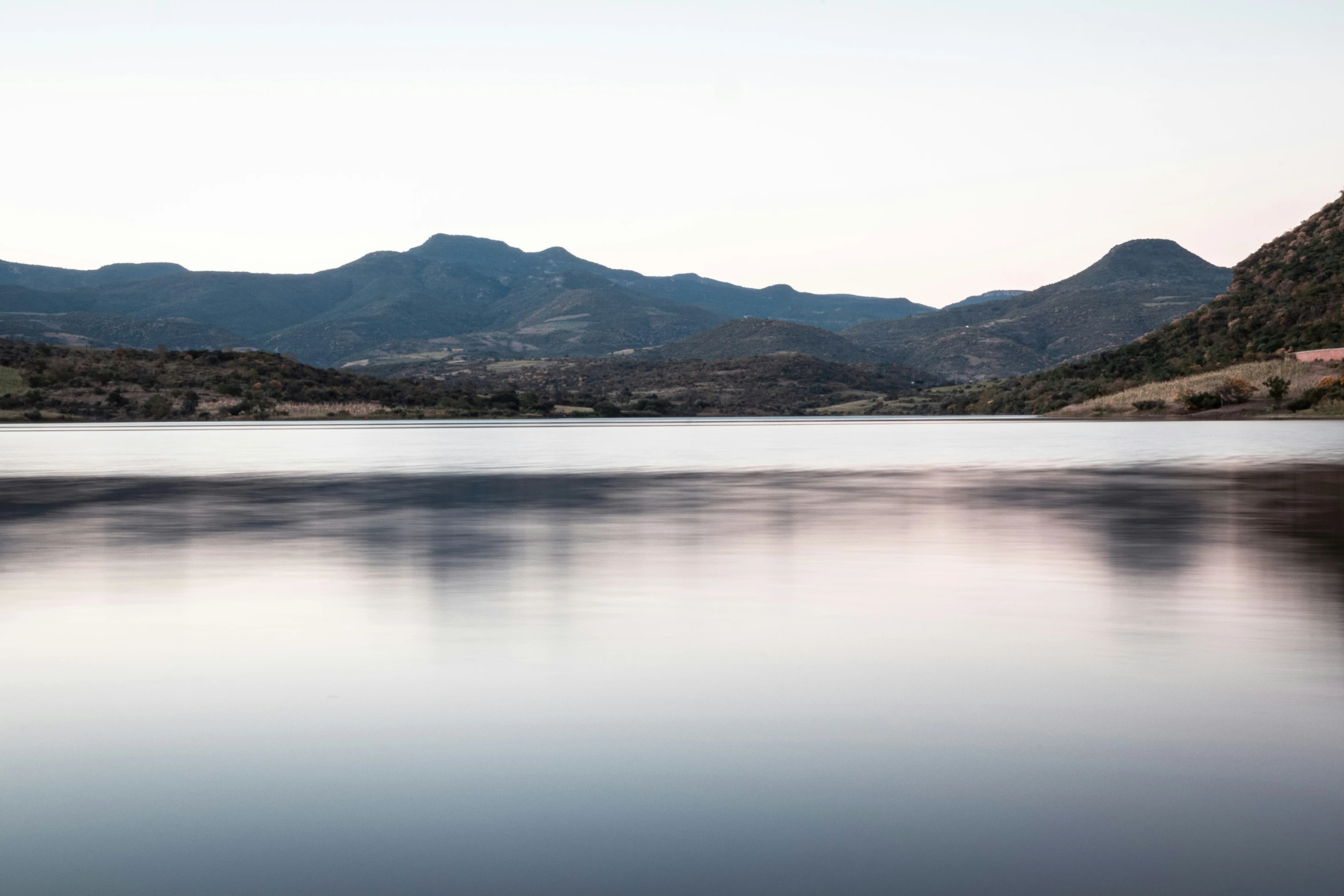 a lake with some water and mountains in the background