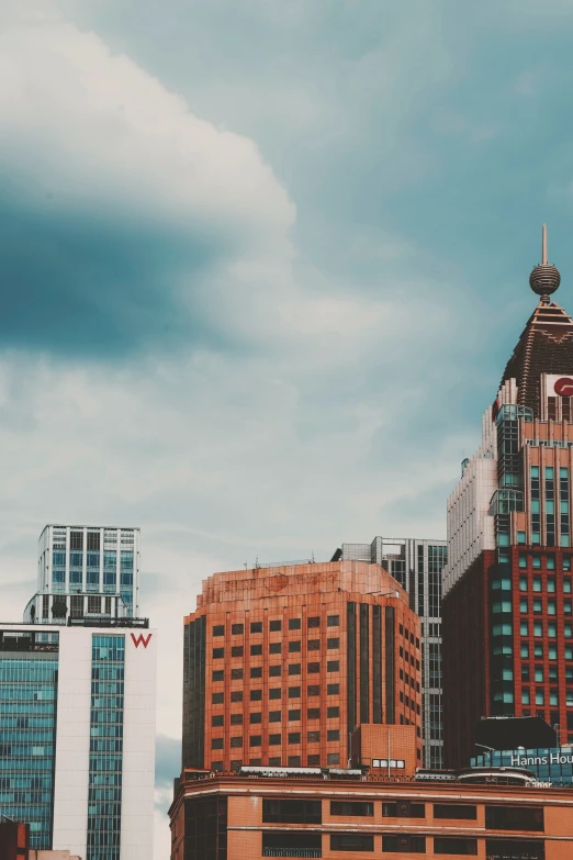 the sky is cloudy as buildings and an airplane fly in the background