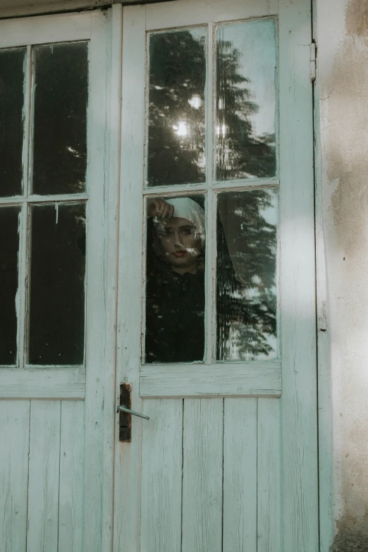 a woman looking out from behind a glassed door