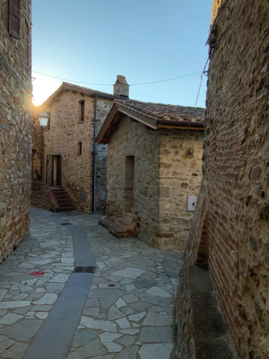 a narrow brick alley with a clock tower on the building