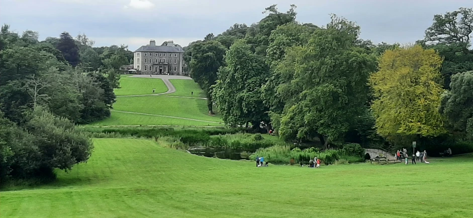 a house with trees on the lawn and people walking