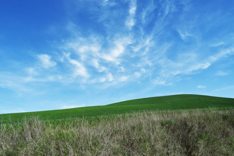 green grassy hills under a partly cloudy blue sky