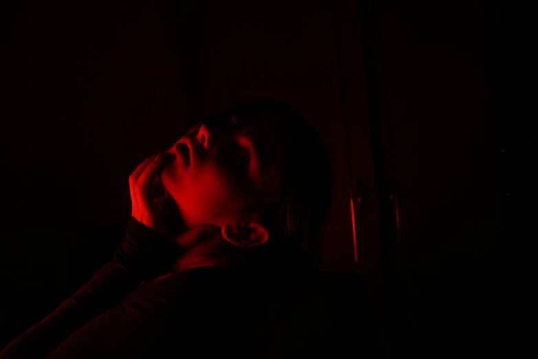 a young woman leaning against a wall, in the dark