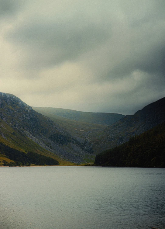 there is mountains and water under the cloudy sky