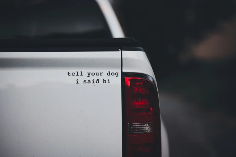 a white truck with sticker written on the back