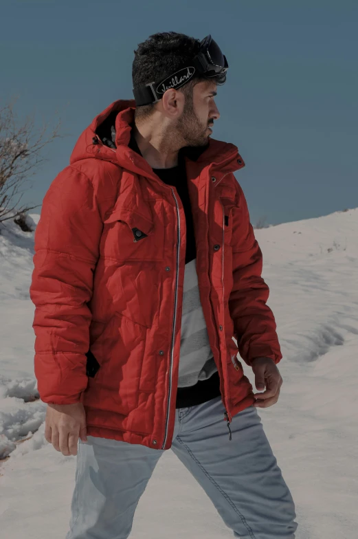 the man is standing in a snowy field wearing a red jacket