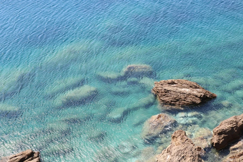 the blue water and green rocks are shown from a cliff