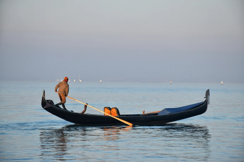 a man standing on the end of a boat in the water