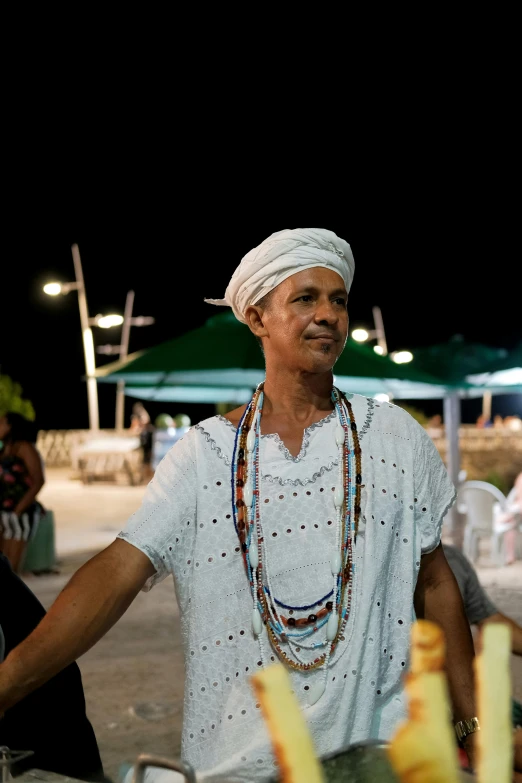 a woman wearing a headdress near some food at an outdoor stand