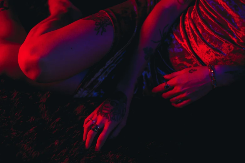 a woman with tattoos laying on a bed in the dark