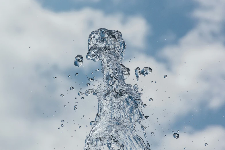 a water spouting in the air with clouds behind it